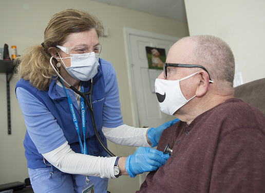 Care Dimensions nurse Nancy Drago listens to the heart of a hospice patient at his home.