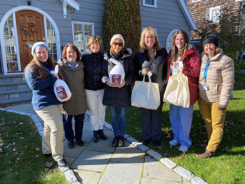 Marblehead Rotary Club Members Linda Sullivan and Nancy Archer Gwin (fourth and fifth from left) present some of the 25 Thanksgiving meals the club assembled for families of children in Care Dimensions’ Pediatric Palliative Care Program. Gratefully accepting the donations from Care Dimensions are Bethany Beers-Mullen, CEO Stephanie Patel, MD, Maureen Burge, Caitlin French, and Angela MacMannus.