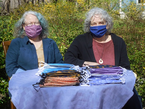 Anne Boedecker and Gail Byrnes display some of the hundreds of homemade masks they’ve donated to Care Dimensions and other organizations.
