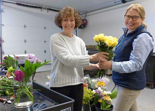 Care Dimensions volunteers Barbara Hopland and Nicole Stephen prepare floral arrangements for placement throughout the Care Dimensions Hospice House.