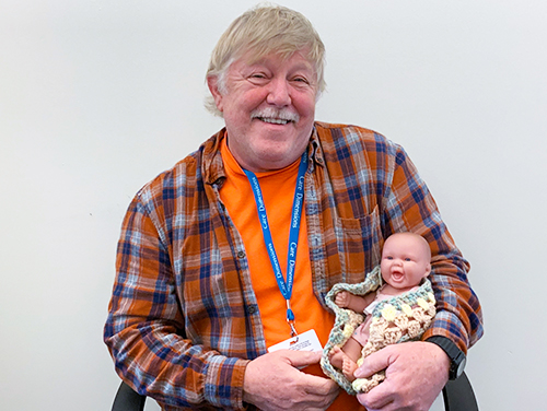 Care Dimensions hospice volunteer Michael Person of Wakefield, Mass., holds a doll that he brings on visits with a patient who has dementia and enjoys dolls.