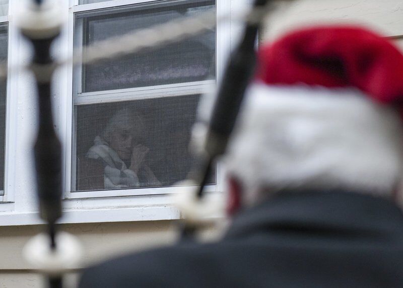hospice patient looks out window at bagpiper in Santa hat