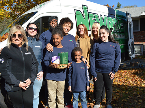 Miriam and Jerome Thomas with two of their children, Anaya and Zia (center), gather outside of their home with NEWPRO and Care Dimensions representatives during their bath makeover.