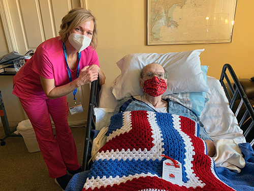 Bob Riley of Peabody, a U.S. Air Force veteran, accepts a Veterans Day gift of a handmade patriotic afghan from his Care Dimensions hospice nurse Jennifer Goodrow. Care Dimensions partnered with the all-volunteer group Hugcrafters, whose members made more than 125 red, white and blue afghans for veterans who are receiving hospice care.