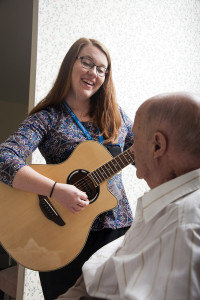 Care Dimensions music therapist Katie Bagley plays guitar for hospice patient