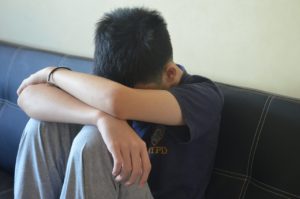 teen boy head down sad grieving