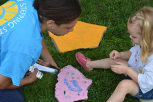 A Care Dimensions Camp Stepping Stones volunteer helps a child with her puzzle piece.