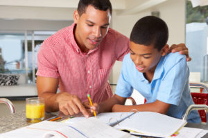 adult male helping boy with homework