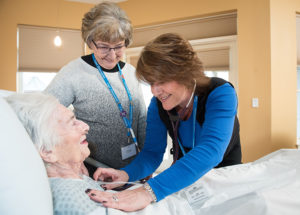 two Care Dimensions hospice nurses caring for female patient in facility