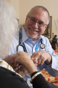 Robert Taylor, MD, Care Dimensions associate medical director for Greater Boston, speaks with a hospice patient during a home visit.