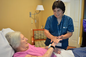 Care Dimensions hospice aide Cindy Berry applies hand lotion for female patient at Kaplan Family Hospice House