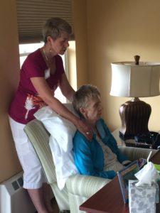 Care Dimensions volunteer Gail Thompson performing Reiki on elderly female hospice patient in chair